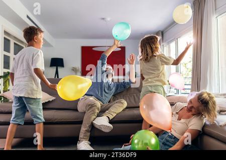 Glückliche Familie spielt gerne mit Ballons im Wohnzimmer Stockfoto