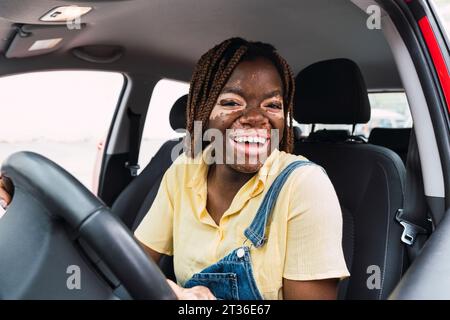 Glückliche junge Frau, die im Auto sitzt Stockfoto