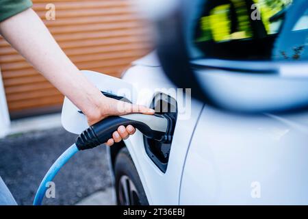 Eine Frau, die ein Elektroauto auflädt Stockfoto