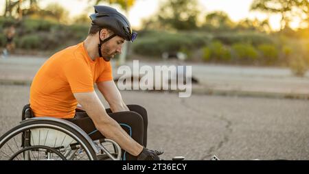 Sportler mit Helm, der auf der Straße im Rollstuhl sitzt Stockfoto