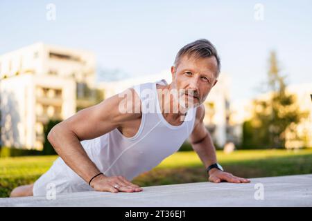 Aktiver Sportler, der Liegestütze im Park trainiert Stockfoto