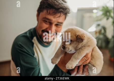 Glücklicher Mann, der einen Welpen mit gemischter Rasse zu Hause hält Stockfoto