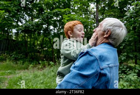 Glücklicher Junge, der mit Großvater im Park spielt Stockfoto