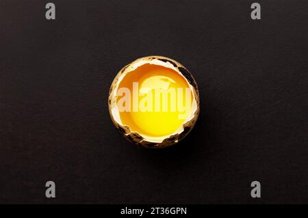 Halb gebrochene Wachteleier auf schwarzem Hintergrund. Draufsicht Stockfoto