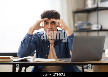 Junger Mann Aus Dem Nahen Osten, Der Kopfschmerzen Hat Und Drinnen Stress Macht Stockfoto
