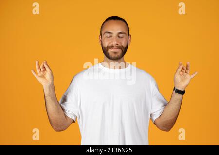 Lachender ruhiger junger kaukasier mit Bart in weißem T-Shirt ruhen, entspannen Sie sich mit geschlossenen Augen Stockfoto