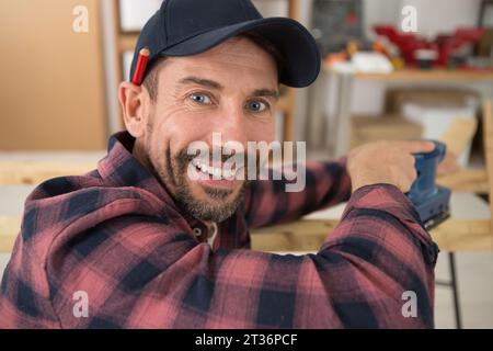 Glücklicher Zimmermann, der Holzdielen schneidet Stockfoto