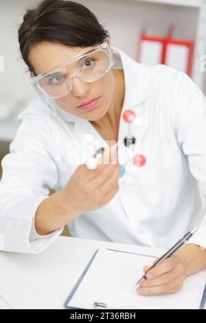 Wissenschaftlerin, die sich ein Molekül-Modell ansieht Stockfoto