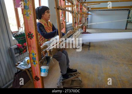 Margilan, Usbekistan - 20. Oktober 2023: Eine Frau, die mit Seide auf einem Webstuhl in Margilan, Usbekistan, arbeitet. Stockfoto