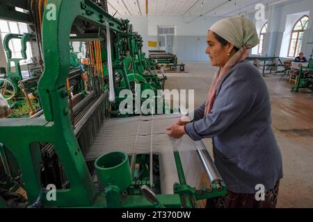 Margilan, Usbekistan - 20. Oktober 2023: Eine Frau, die mit Seide auf einem Webstuhl in Margilan, Usbekistan, arbeitet. Stockfoto