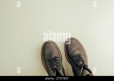 Trendige dunkelgrüne Stiefel auf hellgrünem Hintergrund. Schuhverkauf, Modekonzept. Stylische Schuhe zum Wandern. Draufsicht, flach, Kopierbereich. Stockfoto