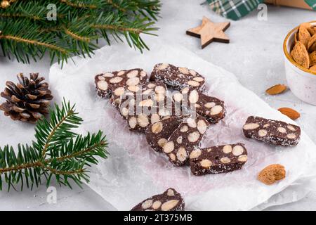 In Scheiben geschnittene Schokoladensalami mit Mandeln auf Backpapier, Weihnachtsdessert Stockfoto