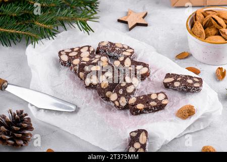 In Scheiben geschnittene Schokoladensalami mit Mandeln auf Backpapier, Weihnachtsdessert Stockfoto