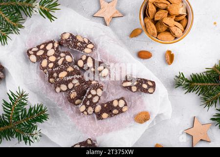 In Scheiben geschnittene Schokoladensalami mit Mandeln auf Backpapier, Weihnachtsdessert Stockfoto