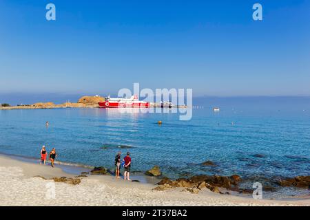 Touristen am Sandstrand, Blick auf die Fähre im Hafen, L'Ile-Rousse, Ile Rousse, Korsika, Frankreich Stockfoto