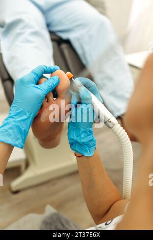 Orthopädischer Arzt in blauen Handschuhen bei der Behandlung der Beine, Nahaufnahme, vertikaler Schuss Stockfoto