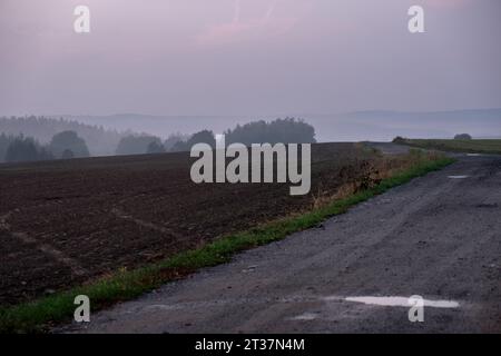 neblige Sonnenuntergangslandschaft gepflügte Feld rote Wolken Stockfoto