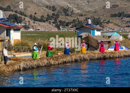 Frauen von schwimmenden Inseln der Uros-Gemeinde empfangen Touristen. Die Uros-Inseln liegen auf einer Höhe von 3.810 m am Titicacasee. Stockfoto