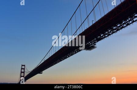 Großformatiger Blick von einem Boot aus, während es unter der berühmten, wunderschönen Golden Gate Bridge bei Sonnenuntergang fährt. Stockfoto