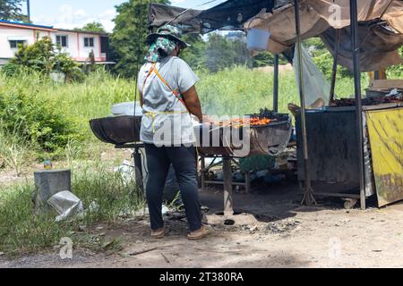 Frauen grillen Fleisch auf einem Grill in einem Straßenrestaurant in Thailand Stockfoto