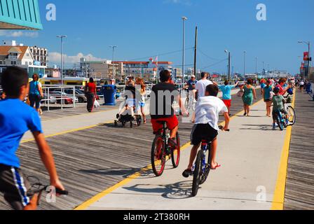 Teenager genießen einen Sommerurlaub, während sie auf dem Wildwood Boardwalk durch die Menschenmenge schlängeln, während sie mit ihren Fahrrädern fahren Stockfoto