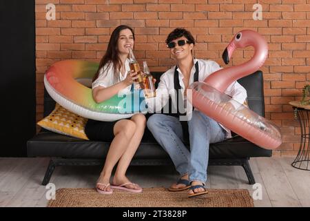 Ein junges Paar mit Bier und Schwimmringen, bereit für den Sommerurlaub im Büro Stockfoto
