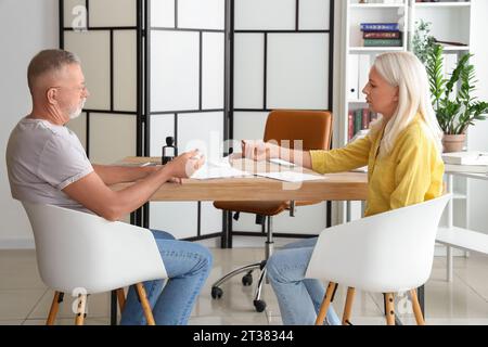 Reifes Paar mit abgenommenen Eheringen im Büro. Scheidungskonzept Stockfoto