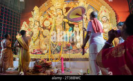 Howrah, West Bengal, Indien - 5. Oktober 2022: Göttliche Shahkh Naad, hinduistische Devotee Frau bläst Muschelschale, während Purohits Göttin Durga verehren. Stockfoto