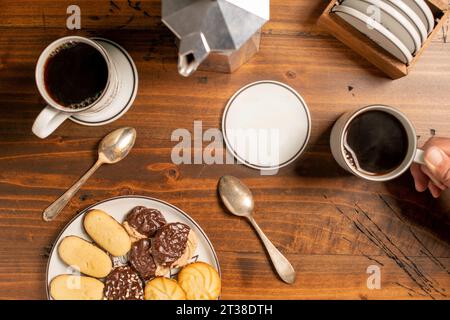 Frischer Kaffee mit Keksen und Handbecher mit Löffeln auf einem Holztisch Stockfoto