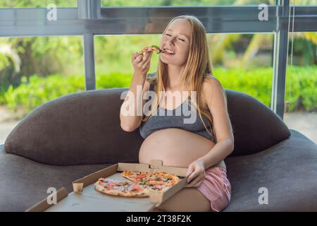 Eine schwangere Frau genießt ein Stück Pizza und genießt einen Moment der Genussfreude, während sie ihr Verlangen nach einer köstlichen, wohltuenden Leckerei befriedigt. Begeistert Stockfoto