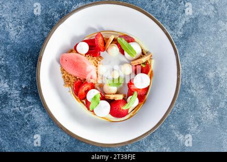 Quenelle aus Erdbeersorbet, Meringue mit Grahm-Cracker-Kruste, überzogen auf blauem Hintergrund Stockfoto