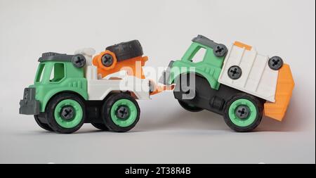 DIY-Kunststoff-Truck-Spielzeug isoliert auf weiß. Schwerlastfahrzeug schleppt beschädigten Müllwagen ab. Das selbstgebaute Spielzeug steigert die Kreativität der Kinder. Stockfoto