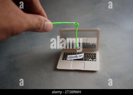 Nahaufnahme des Laptops und Fischhaken mit PERSÖNLICHEN TEXTINFORMATIONEN. Phishing-Angriffskonzept Stockfoto