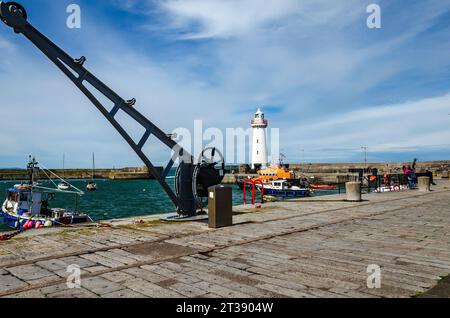 Donaghadee, County Down, Nordirland, 05. August 2023 - Donaghadee Leuchtturm mit RNLI Rettungsboot im Hafen und alten Kran mit Kopierraum Stockfoto
