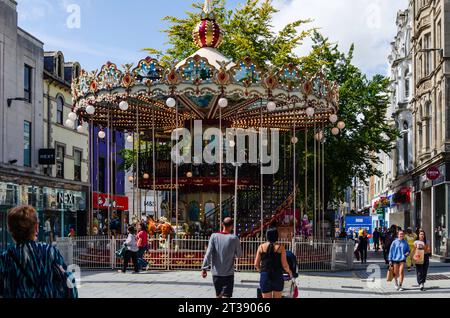 Cardiff, Glamorgan, Wales, 11. August 2023 - Ein zweistufiges Karussell im Zentrum von Cardiff mit Einkäufern auf der Straße Stockfoto