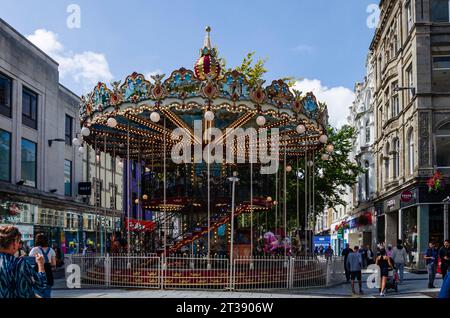 Cardiff, Glamorgan, Wales, 11. August 2023 - Ein zweistufiges Karussell im Zentrum von Cardiff mit Einkäufern auf der Straße Stockfoto