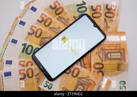 Athen, Griechenland. Oktober 2023. In dieser Fotoabbildung wurde ein Münz98-Logo auf einem Smartphone-Bildschirm auf 50- und 100-Euro-Rechnungen in Athen, Griechenland, am 24. Oktober 2023 gezeigt. (Foto-Illustration von Nikolas Kokovlis/NurPhoto) Credit: NurPhoto SRL/Alamy Live News Stockfoto