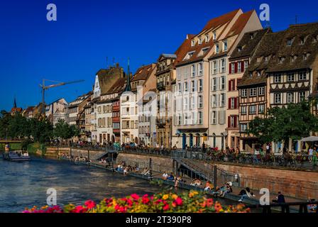 Straßburg, Frankreich - 31. Mai 2023: Menschen spazieren entlang des Ill River und traditionelle Fachwerkhäuser mit steilen Dächern im historischen Zentrum Stockfoto