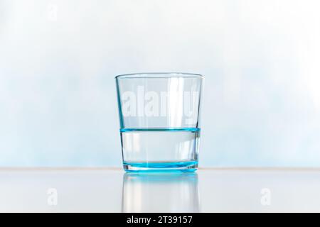 Klar und Glas Wasser. Blaues Glas mit klarem Wasser auf blauem Hintergrund Stockfoto