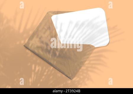 Ein Umschlag mit einem Blatt strukturiertem weißem Papier auf gelbem Tischhintergrund. Mockup mit einer Überlagerung tropischer Pflanzenschatten. Natürliches Licht macht shado aus Stockfoto