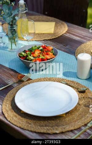 Tischaufstellung bei einer Sommergartenparty. Gartenparty-Tisch mit frischem Gemüsesalat, Gläsern, Limonade, frischem Obst und zartem Blumenschmuck. Stockfoto