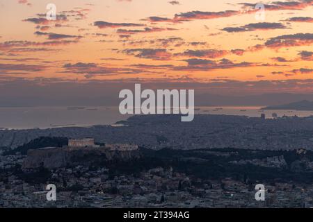 Ein Blick auf den Sonnenuntergang von Athen, vom Lycabettus in Richtung Hafen und Docks. Das Parthenon ist in der Mitte des Bodens sichtbar. Stockfoto