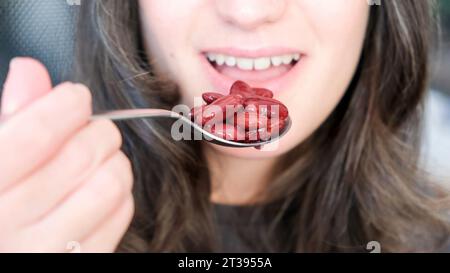 Eine Frau genießt eine köstliche Schüssel mit Schokoladenkugeln, einen Löffel in einer Hand Stockfoto