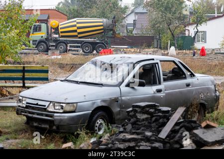 Irpin, Ukraine. Oktober 2023. Ein Betonmischer arbeitet hinter einem Auto, das während des Angriffs der russischen Armee im Frühjahr 2021 zerstört wurde. Die Stadt in der Nähe von Kiew wurde durch schwere Kämpfe teilweise zerstört. In der Zwischenzeit hat der Wiederaufbau Fortschritte gemacht. Quelle: Sebastian Gollnow/dpa/Alamy Live News Stockfoto