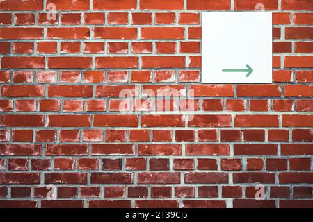 Richtungspfeilschild an der Backsteinfassade mit Kopierraum Stockfoto