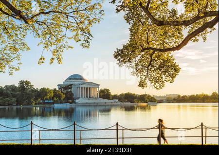 Seitenansicht einer anonymen Frau in sportlicher Kleidung, die am Ufer des Potomac am Jefferson Memorial Monument im Herbstpark am sonnigen Tag auf dem Ufer spaziert Stockfoto