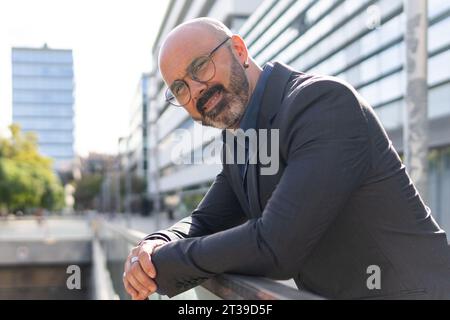 Seitenansicht eines Porträts eines bärtigen und kahlen Geschäftsmannes, der auf der Straße in die Kamera schaut Stockfoto
