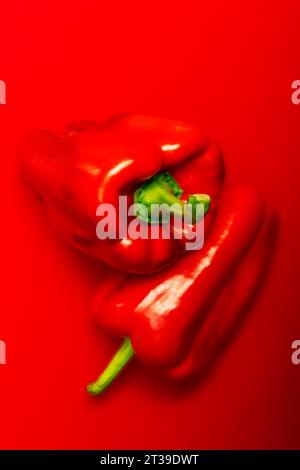 Draufsicht der Reifen roten Paprika, die übereinander vor rotem Hintergrund platziert werden Stockfoto