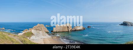 Panoramablick von oben auf den Strand von Arnia mit schroffen Klippen, azurblauem Wasser und ruhigen Landschaften unter einem klaren blauen Himmel in Kantabrien, Spanien Stockfoto