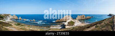 Panoramablick von oben auf den Strand von Arnia mit schroffen Klippen, azurblauem Wasser und ruhigen Landschaften unter einem klaren blauen Himmel in Kantabrien, Spanien Stockfoto